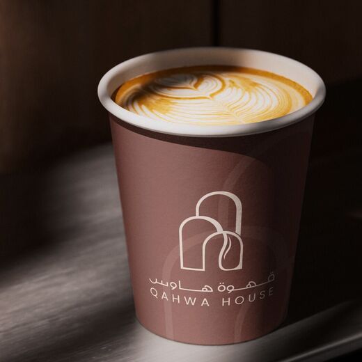A brown Qahwa House takeaway cup with latte art