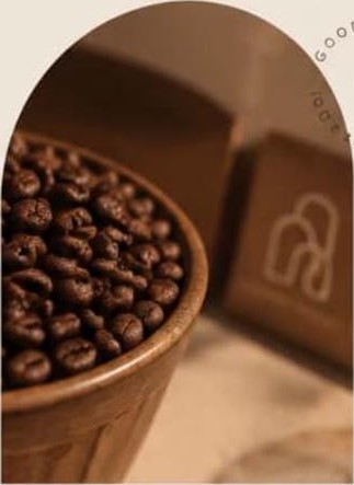 Roasted coffee beans in a wooden bowl beside a Qahwa House box